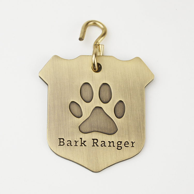 Gold dog tag with paw print and BARK Ranger lettering